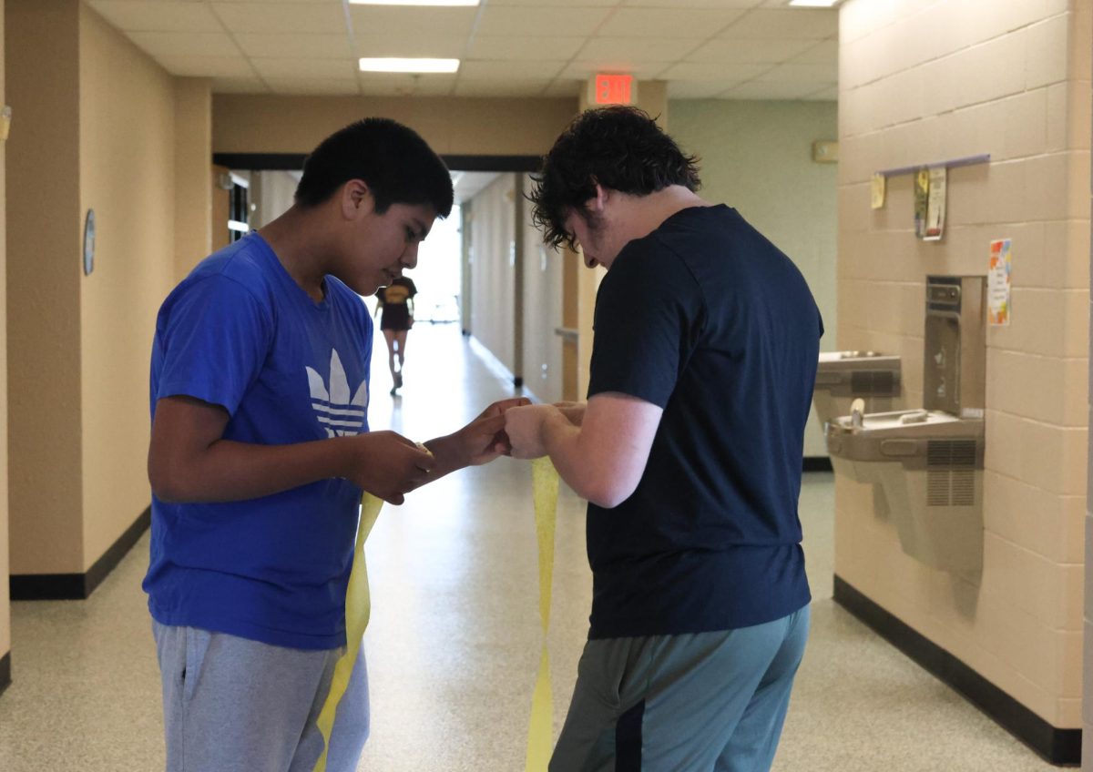 Freshman Alberto Anaya helps freshman William Turvey twist the streamers 
