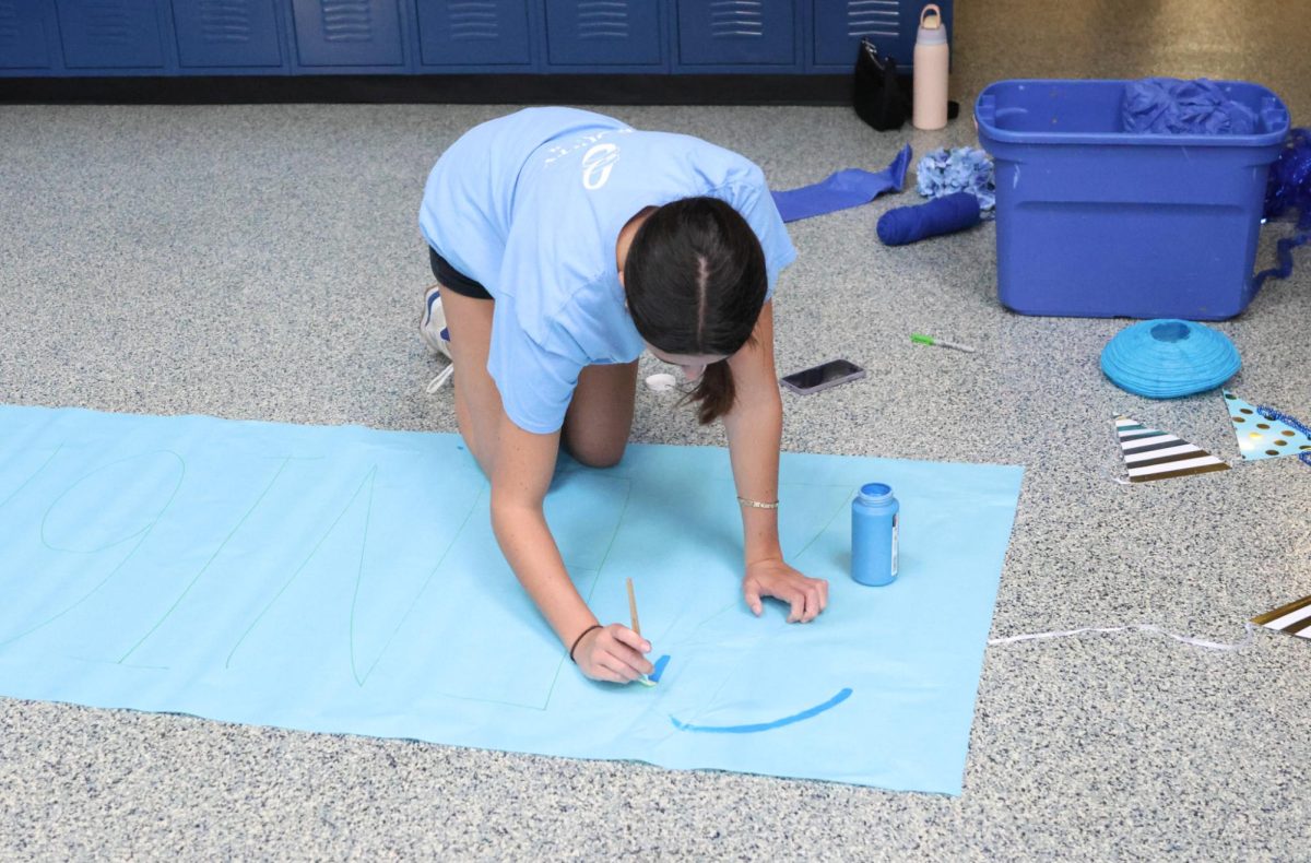 Senior Paige Roth works on painting the senior sign

