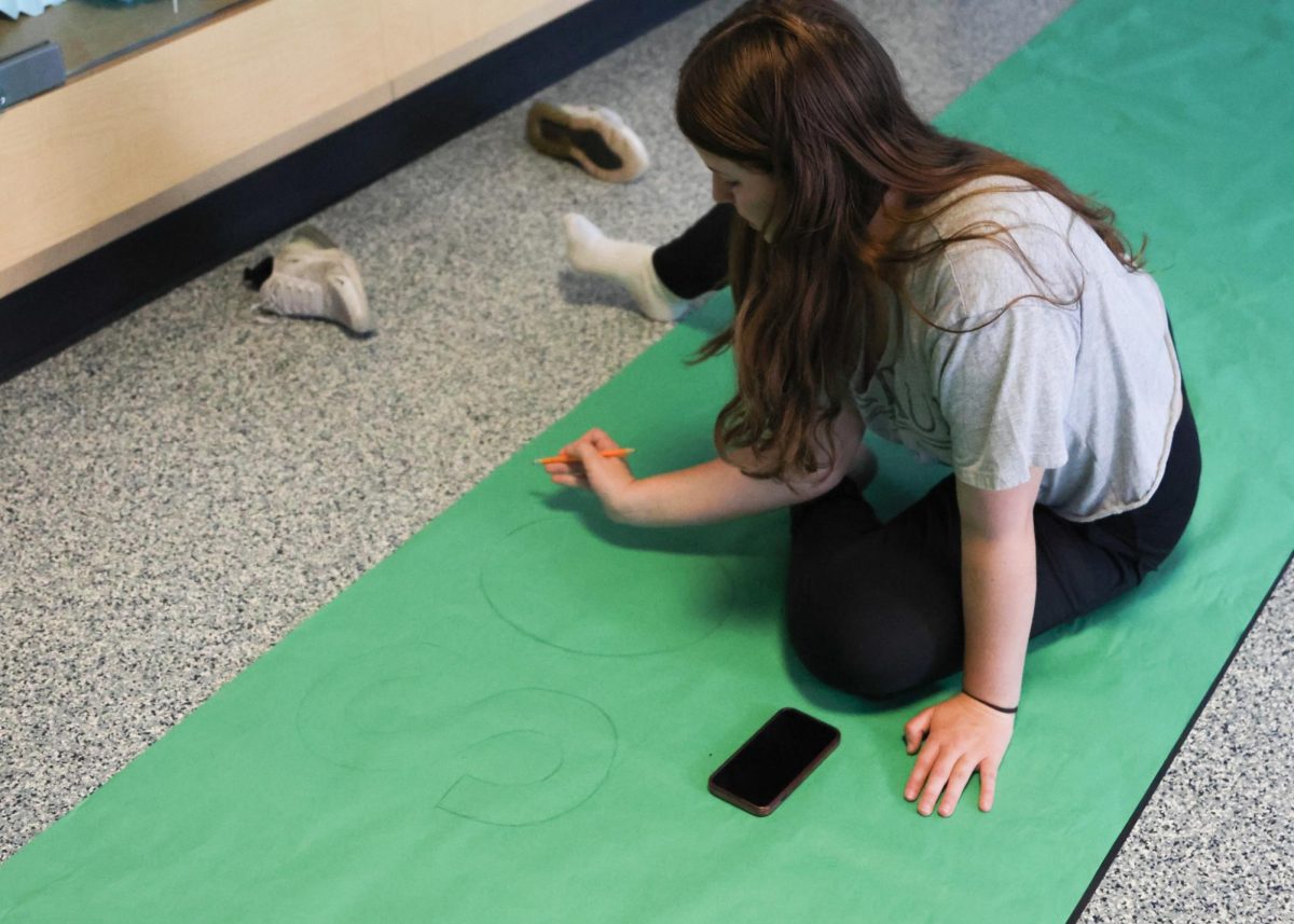 Sophomore Isabel Mohr writes on the sophomore banner 