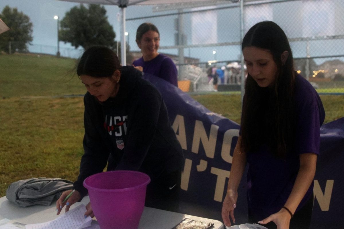 Sophomore Nora Claycamp and Senior Lilly Feuerborn sell ducks and donuts at the entrance to the RFL Purple Out soccer game, Tuesday Sept. 23.