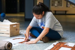 Coloring, junior Natalia Castillejos-Ramirez creates a banner for the Homecoming dance.
