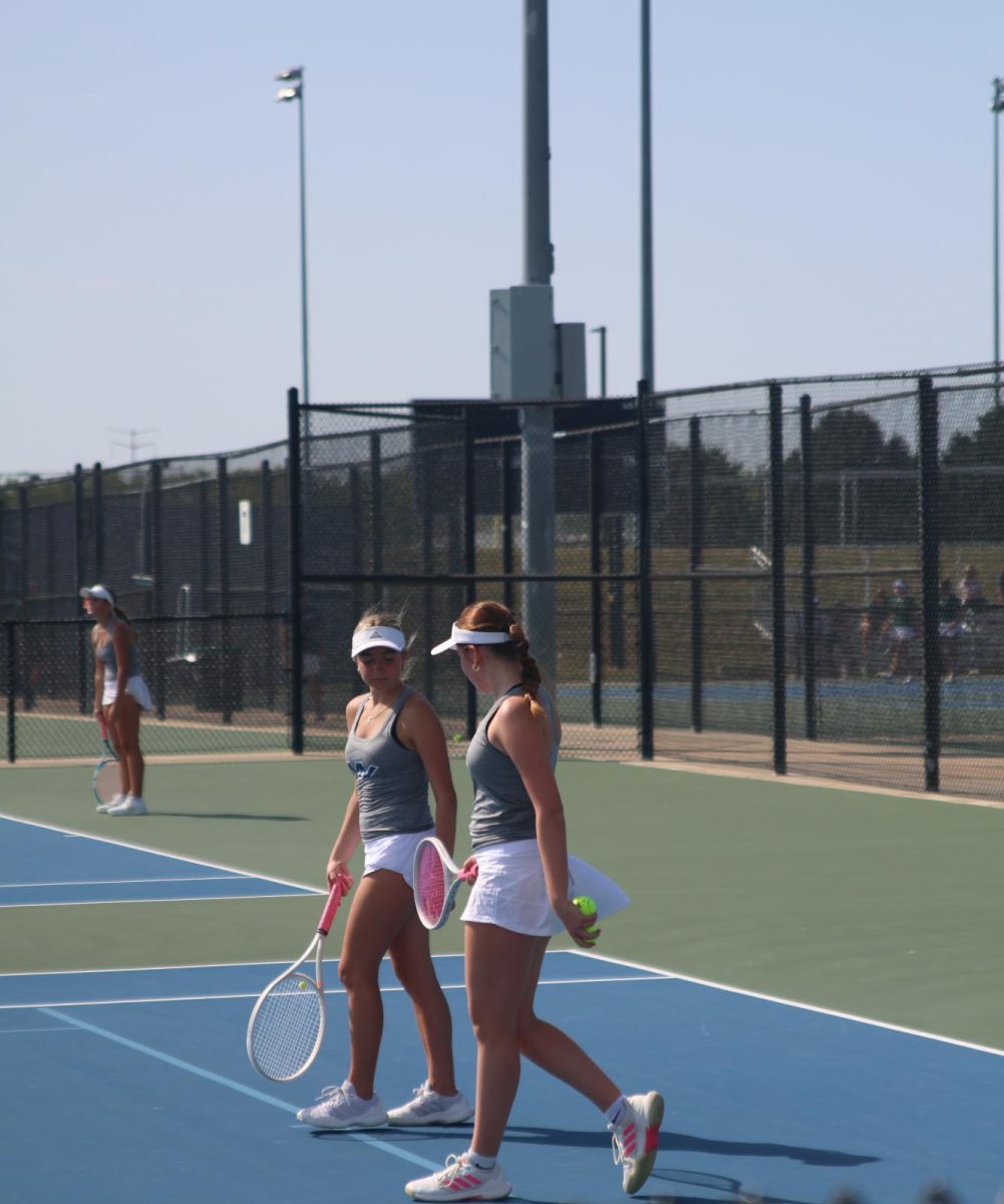 Junior Ella Ericson and sophomore Zoe Wendel chat while walking off the court. 
