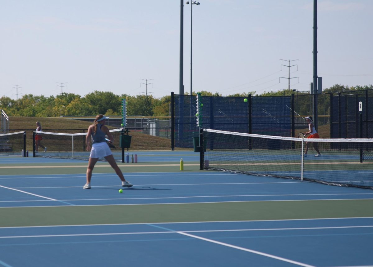 Junior Clara Budimlija hits ball back and forth with opponent from other school. 