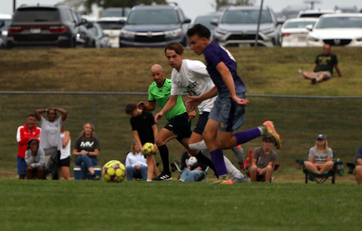 The players run for the ball with the referee keeping a close eye. 