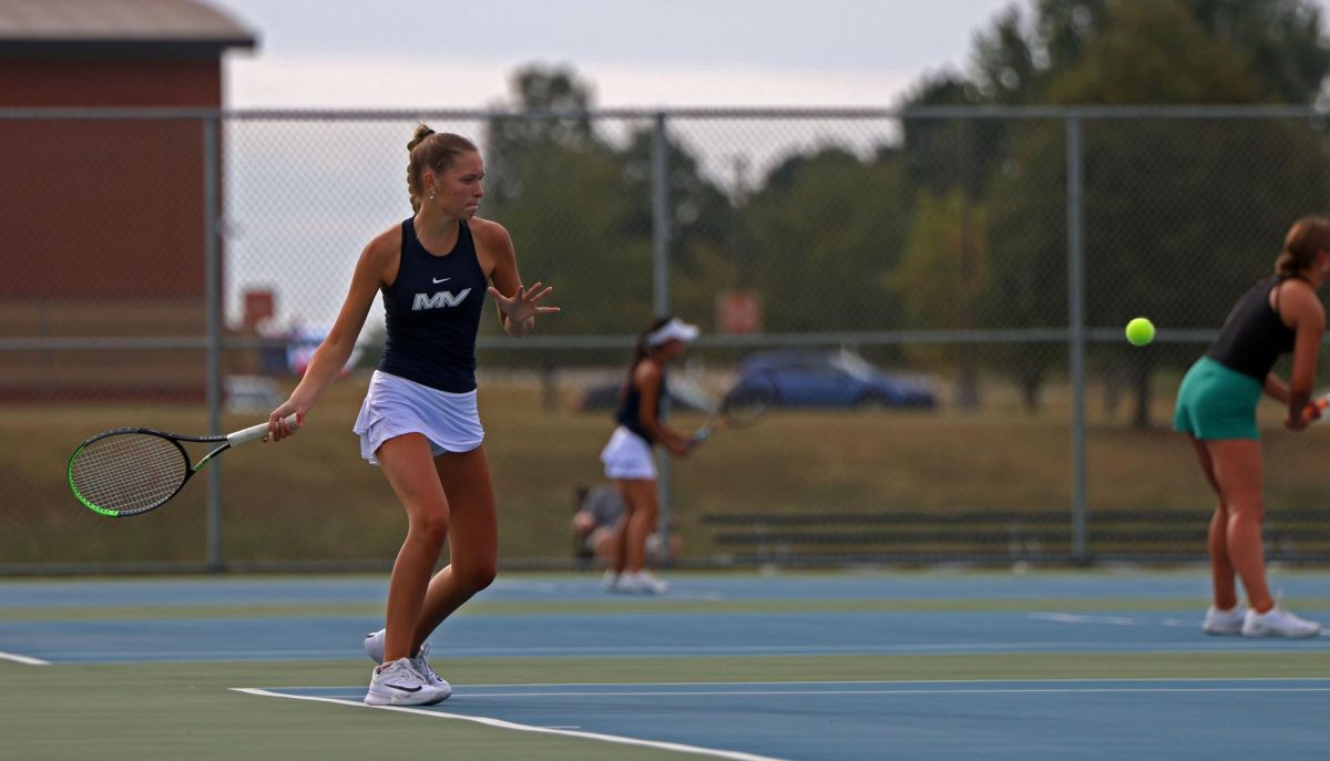 Tossing the ball in the air, senior Bryn Foltz gets ready to serve.

