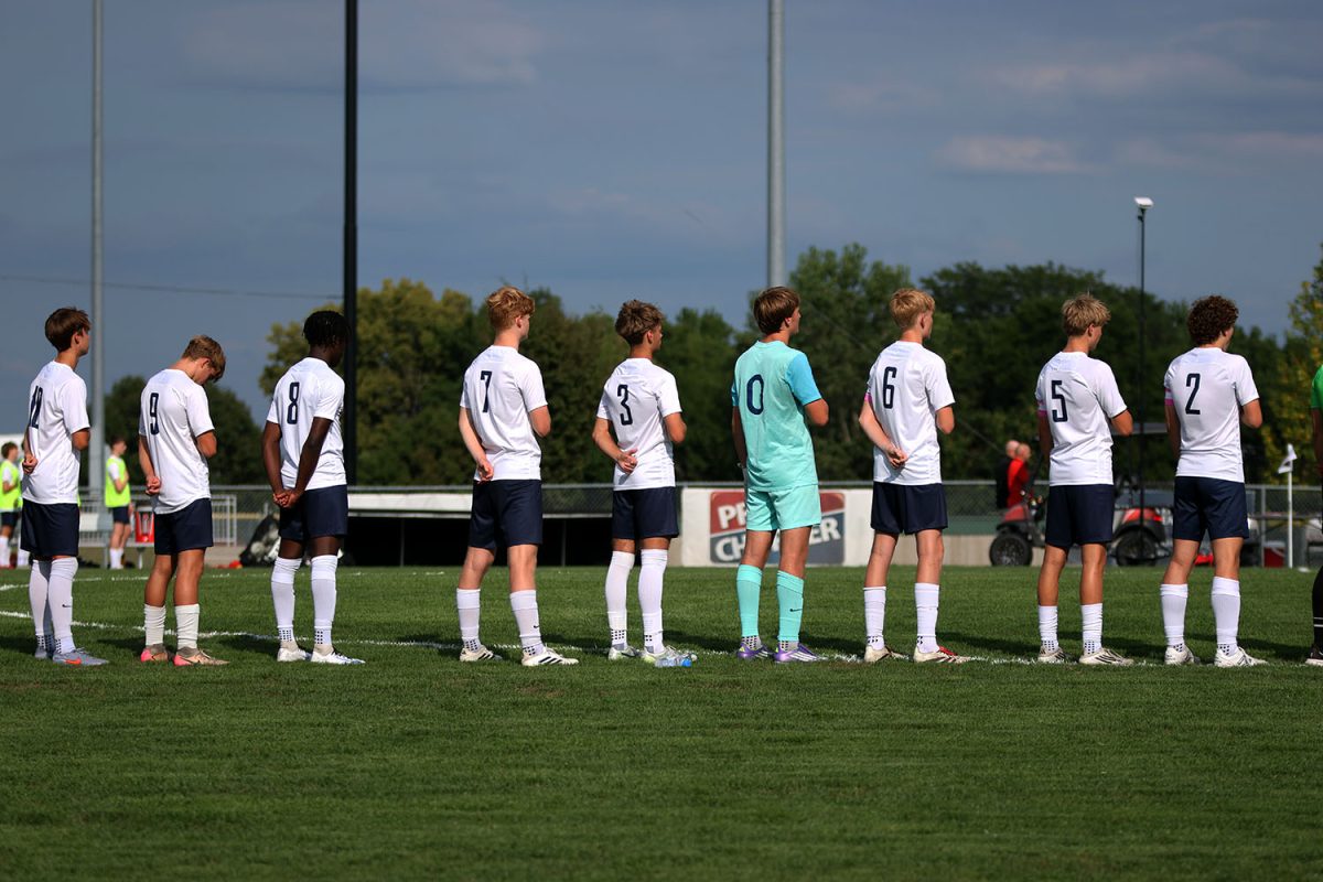 Players stand in a line while they take a moment of silence for the national anthem. Tuesday Sept. 2.