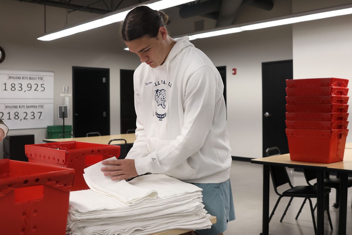 Focusing on not trying to wrinkle the towel, senior Keegan Wootton volunteers at Heart to Heart, Thursday, Sept. 18.