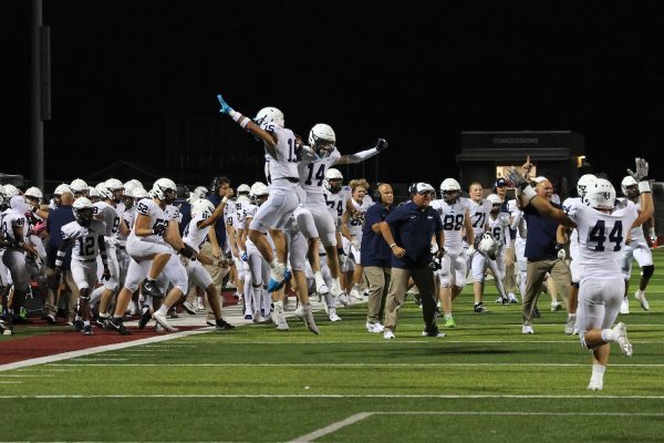 The football team crashes together in celebration after a favorable call is made on the field. 