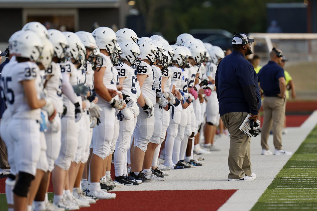 The football team lines up before the game while waiting for the coin toss.

