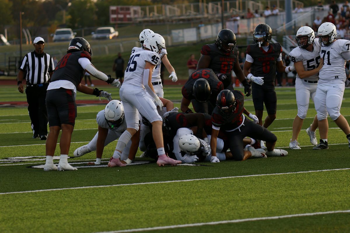 The football team runs the ball, picking up one or two yards.
