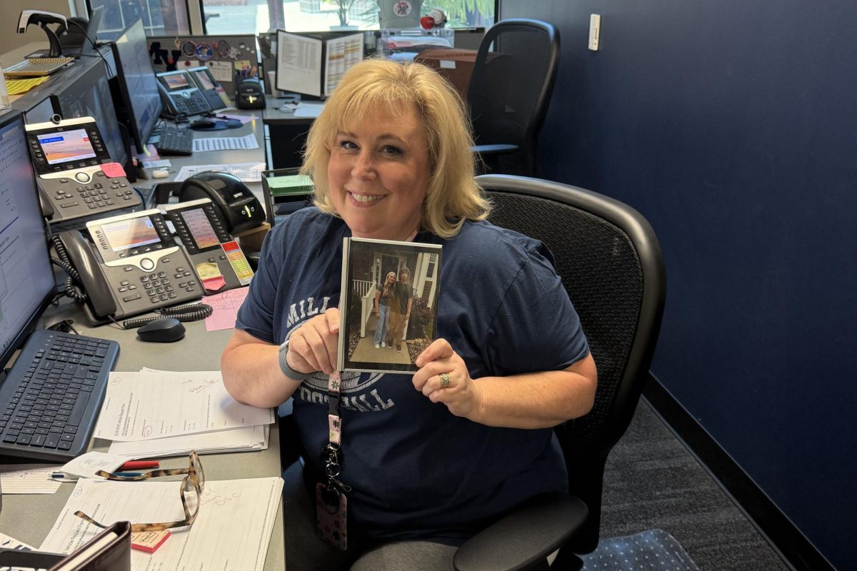 Office secretary Jennifer Hansen poses with a framed photo of her kids she displays on her desk.  