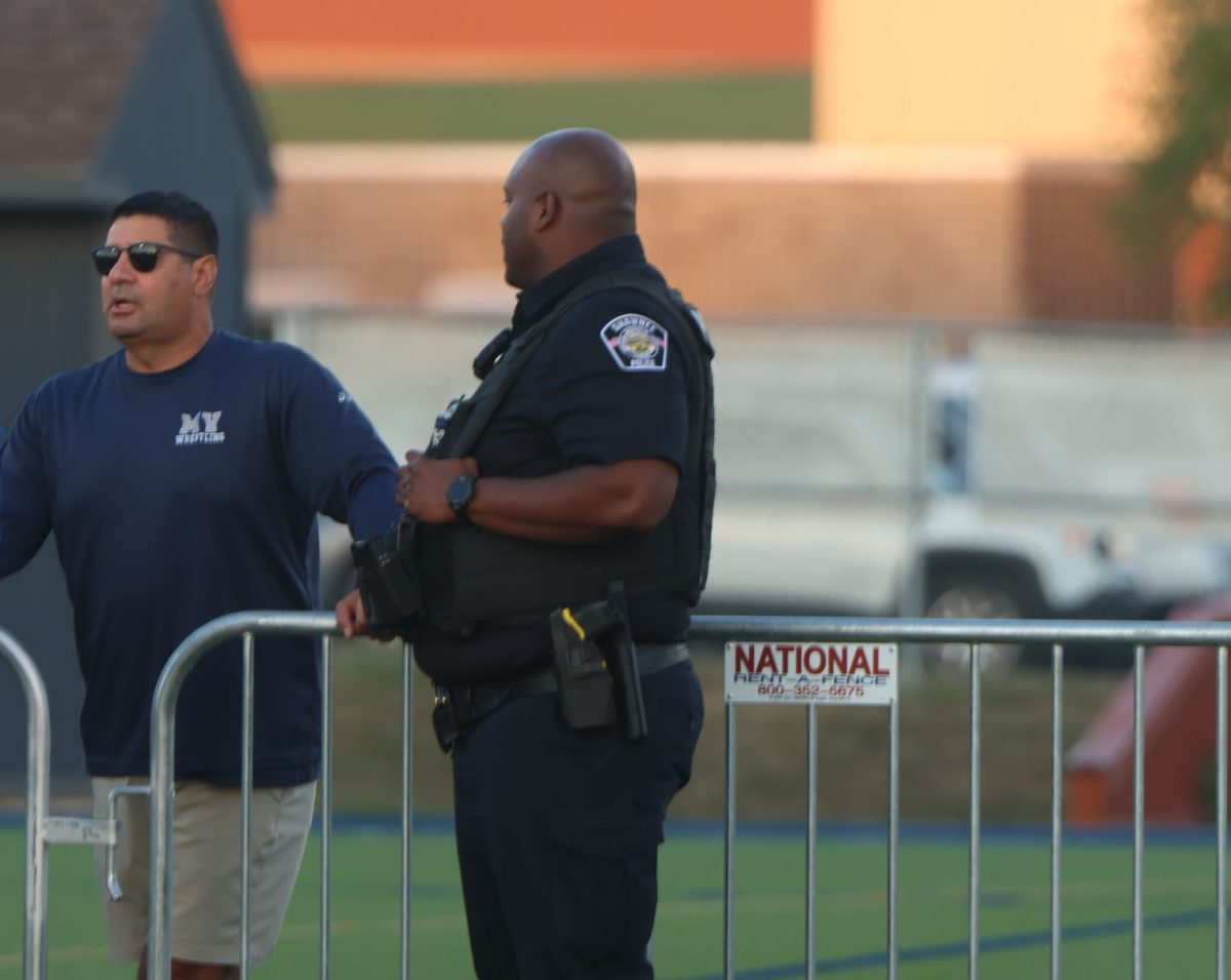 officer Darion Hillman
and former coach Travis Keal waiting for the varsity game to start. 