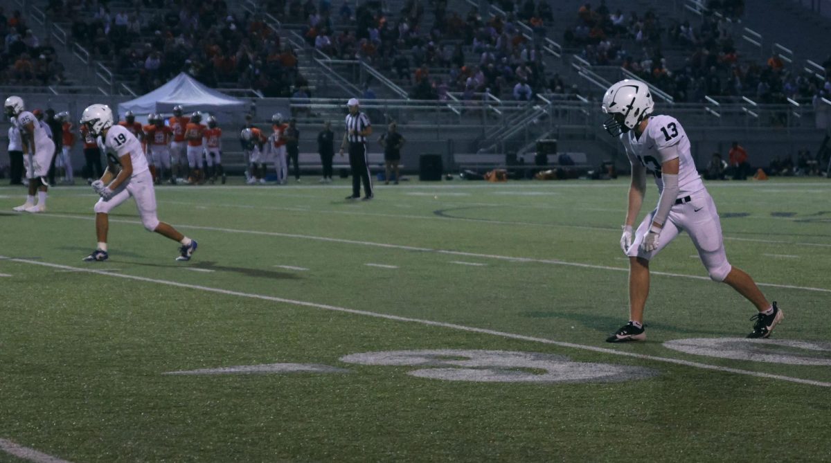 Senior Reegie Reece, junior Anthony Clem, and senior Bryce Shorten stand in formation waiting for the play.