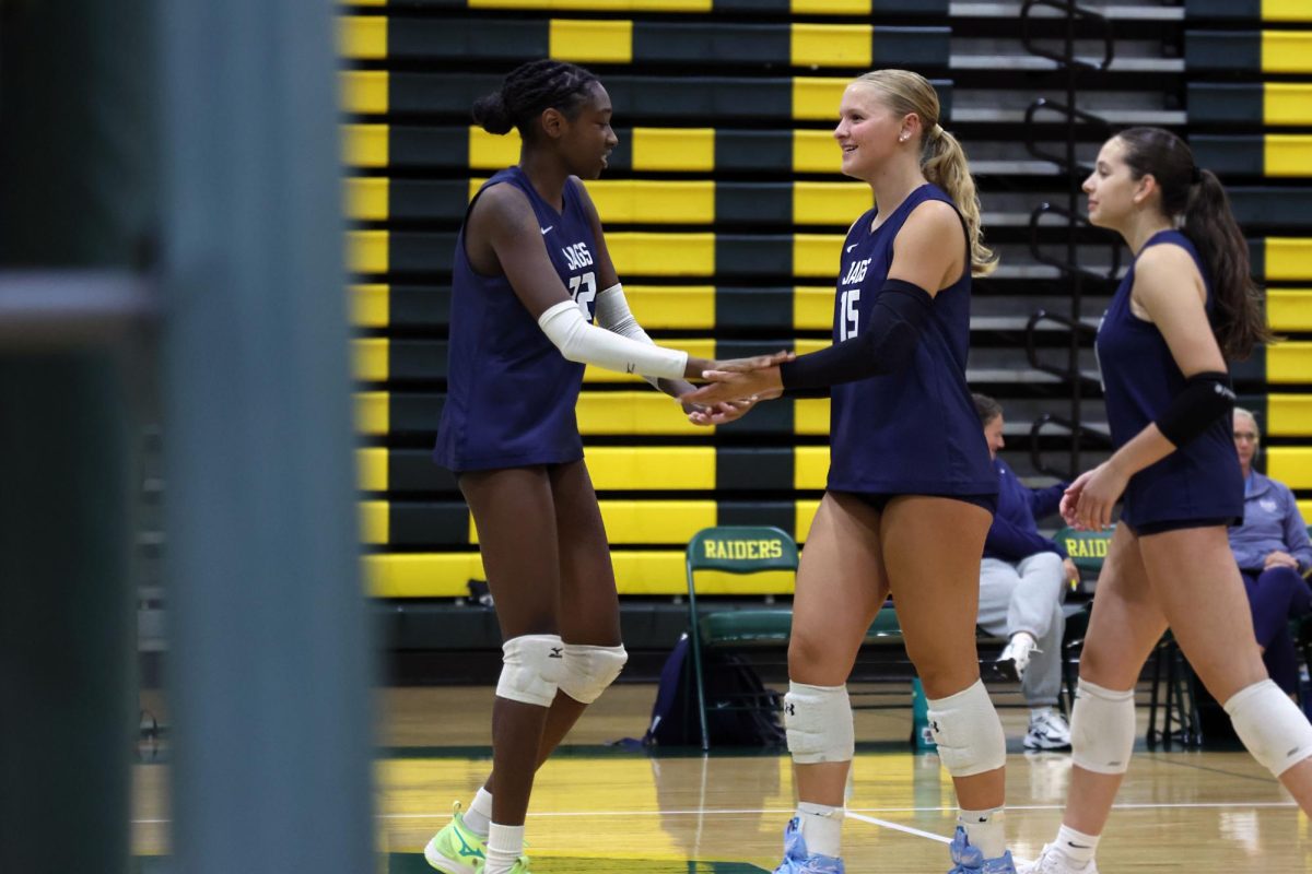 Smiling, junior Josie Danielson and senior Olivia Nzioki high-five each other Thursday Sept. 4 