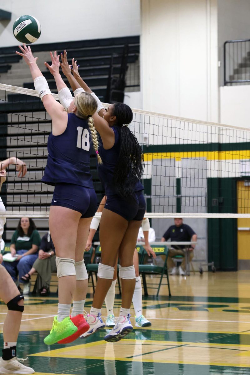 Jumping, junior Riley Riggs and senior Leilah Perry block the ball. 
