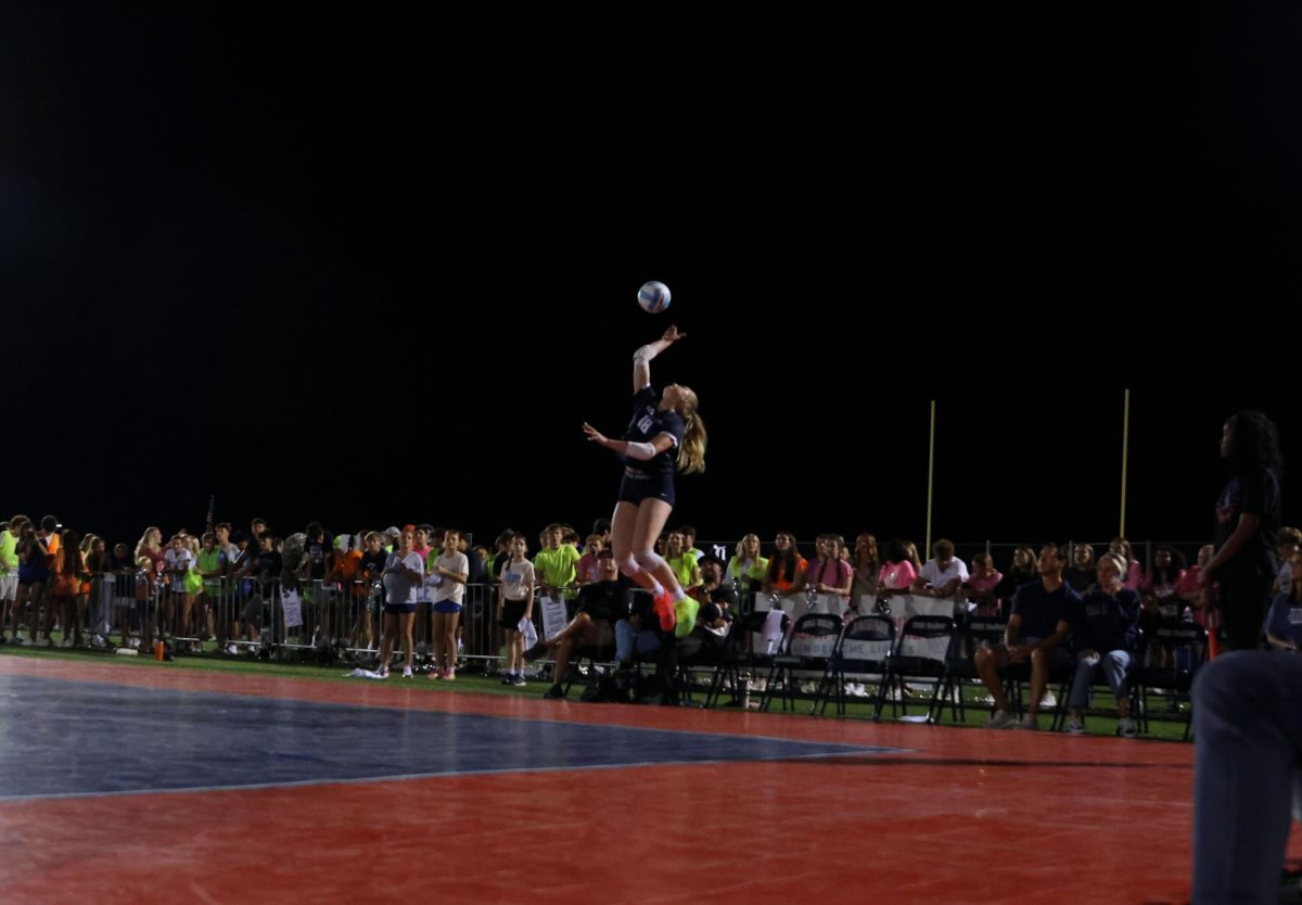 Jumping to serve, all eyes are on junior Riley Riggs.