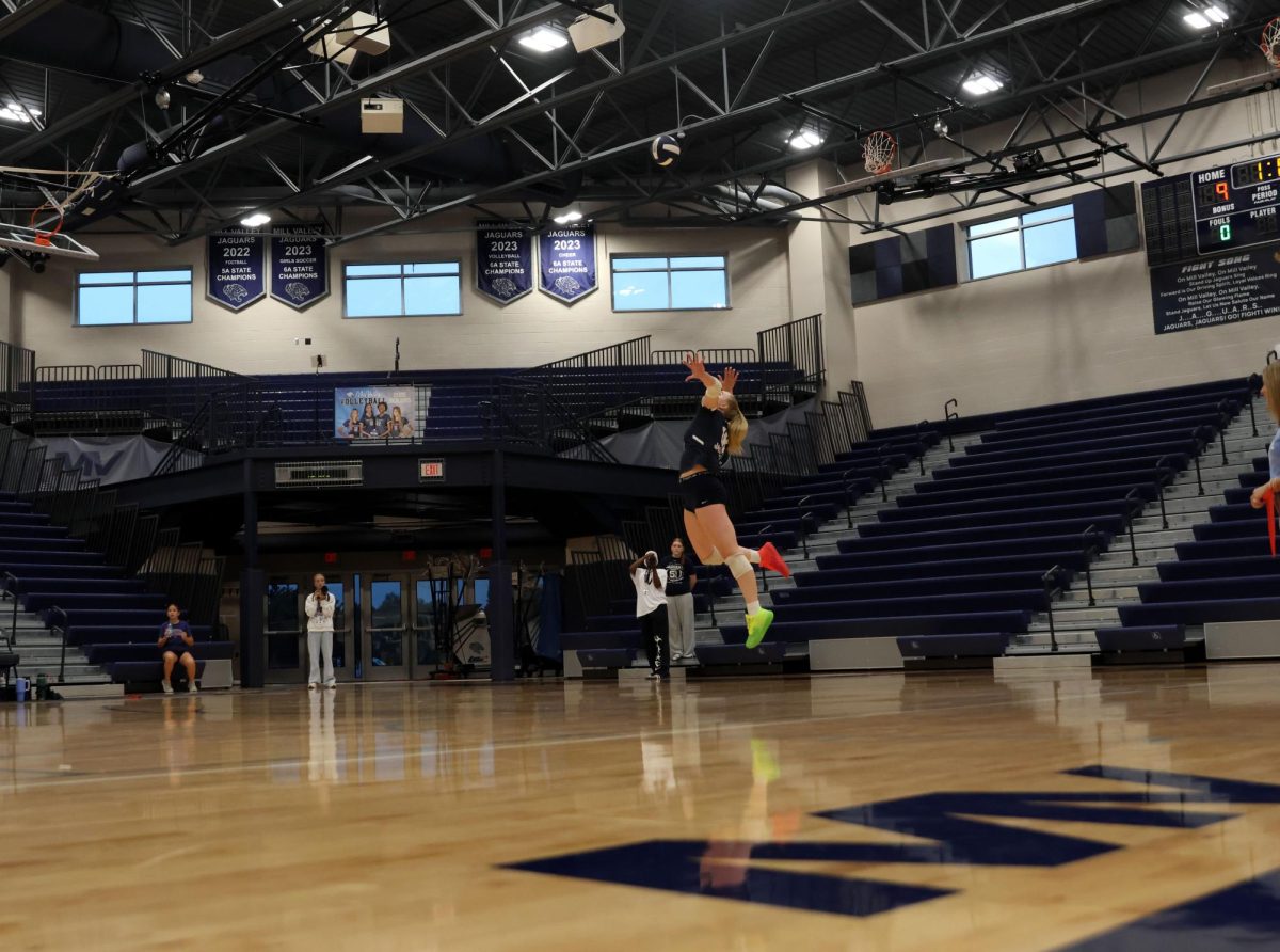 Serving the ball, junior Riley Riggs throws her top spin.