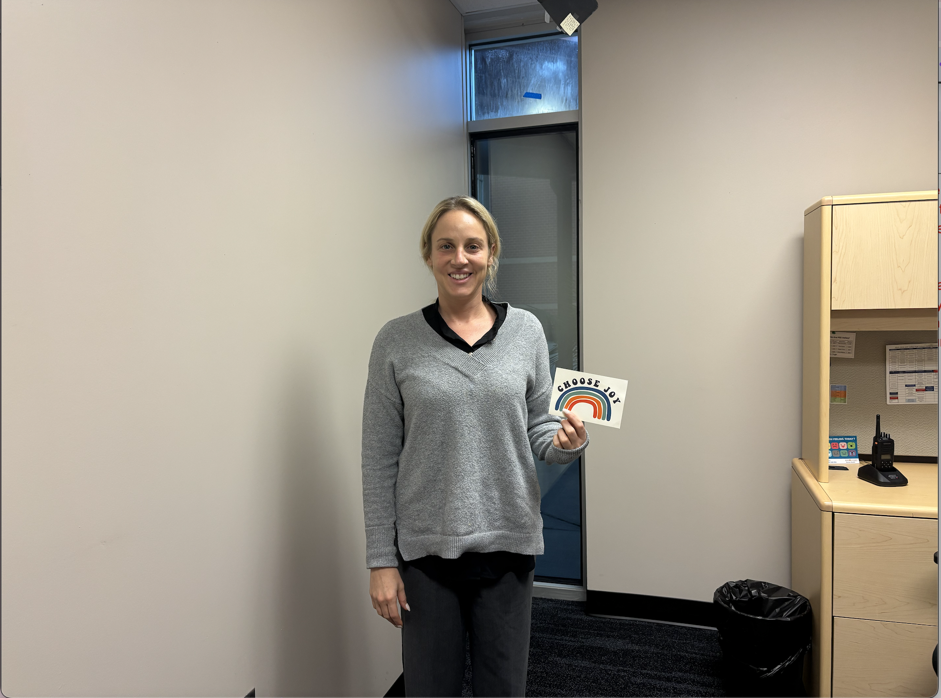 Assistant principal Erin Kessler holds up her choose joy sign, she enjoys having it in her office to remind herself to stay positive. 