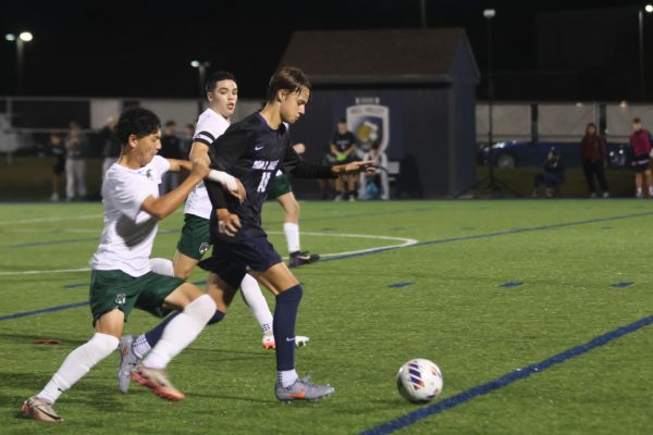 Senior Graham Kruger dodges opposing players to keep possession of the ball before passing it, Tuesday Sept. 23.