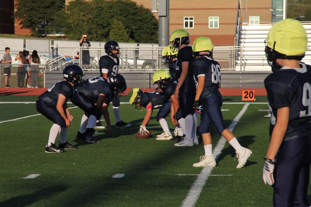 Youth players line up at the line of scrimmage, focused and ready for the next play. With helmets on and eyes locked in, it’s game time under the afternoon sun.