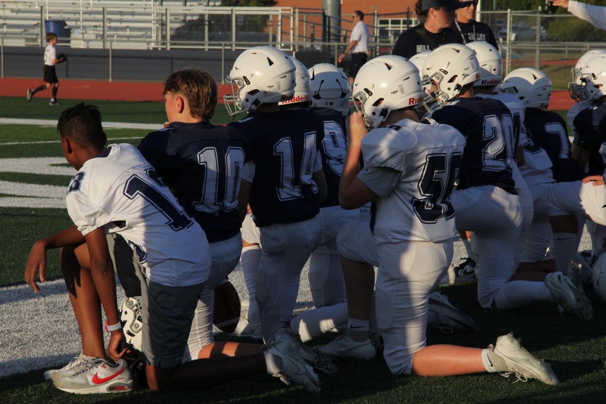 Locked in and learning, the team takes a knee during a timeout, focused on the next play and supporting each other from the sidelines.