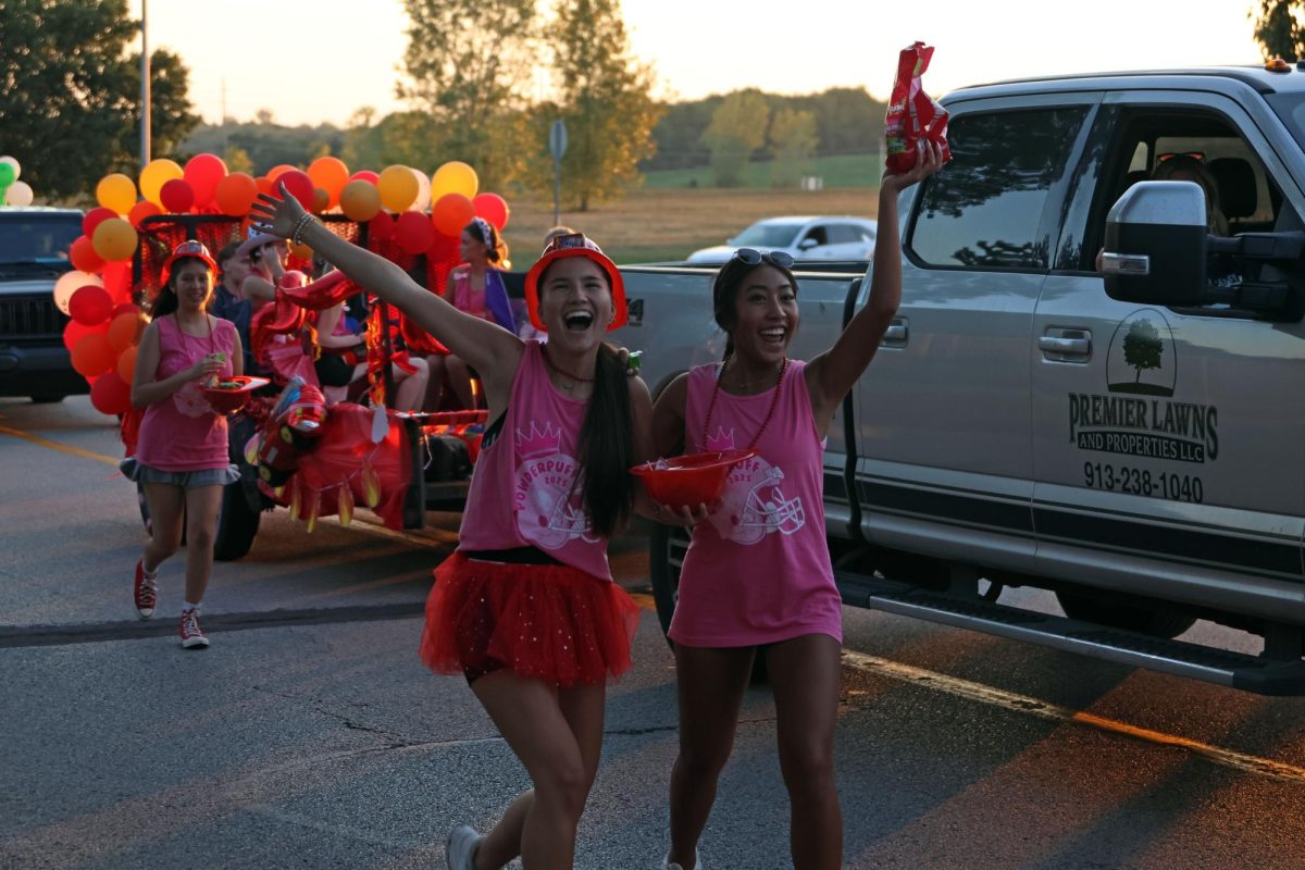 Juniors Caitlin Pham and Lyci Manirad shout and throw candy to the people watching the homecoming parade.
