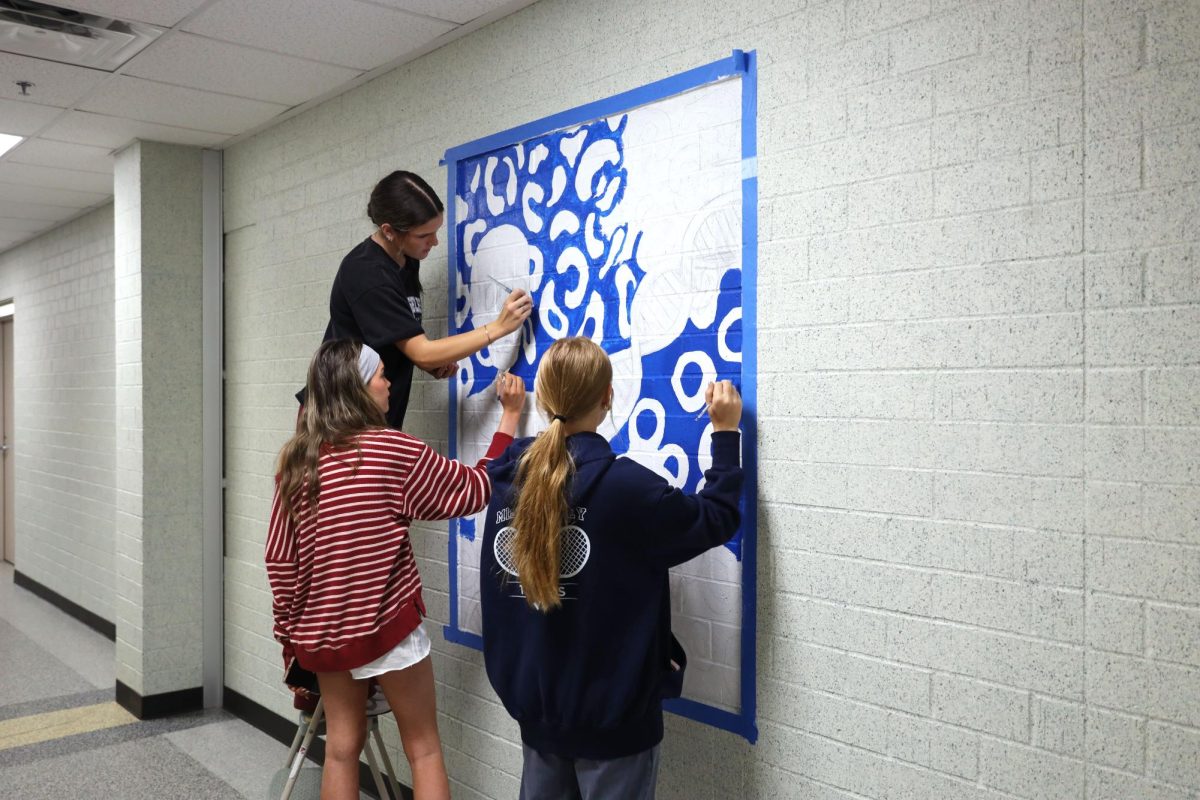 Seniors Kaitlyn Tracy and Hayli Scheffler and junior Clara Budimlija work together to paint the background of their mural Oct. 14.