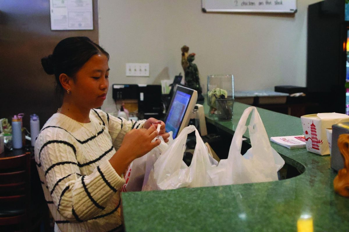Helping out at her parents’ restaurant after school, sophomore Hollie Chen packages orders to hand out to customers, Wednesday Oct. 15.