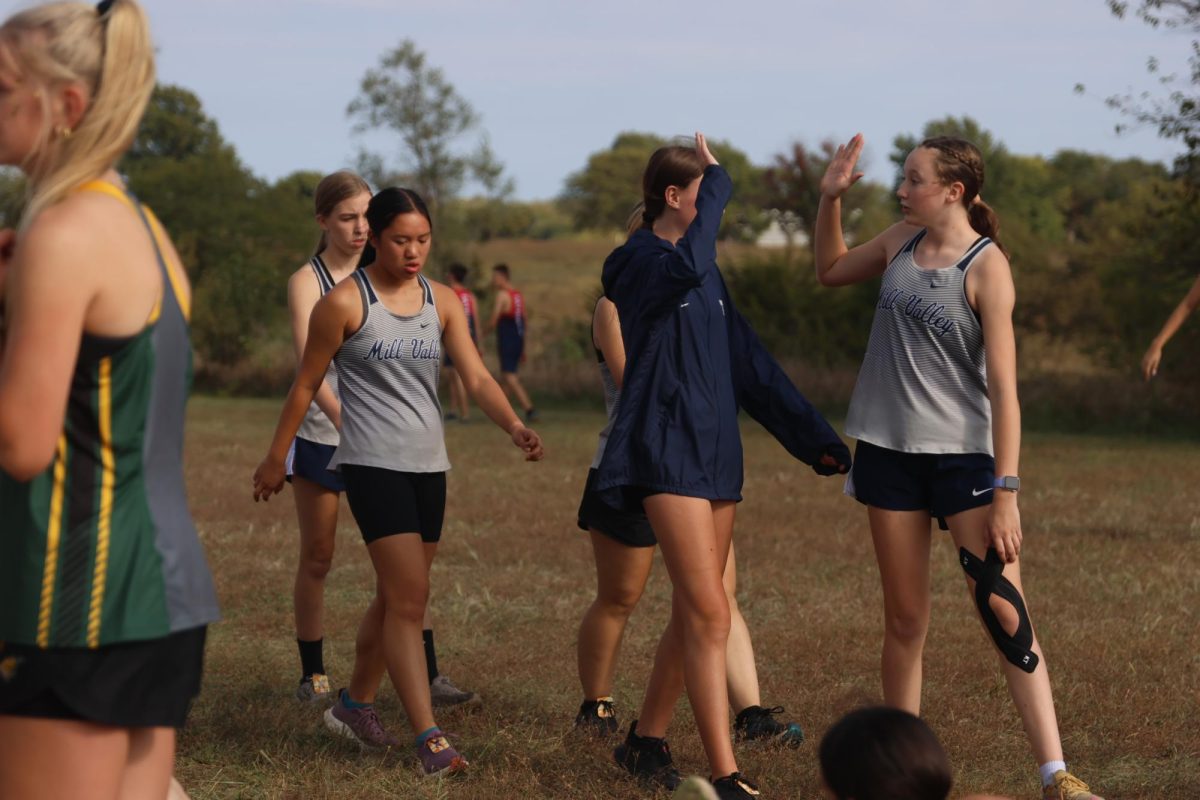 Freshman Rylee Hugart and Sophomore Addi Ritcher high-five each other after the race, along with sophomore Effie Niewohner and junior Violet Toepfer.
