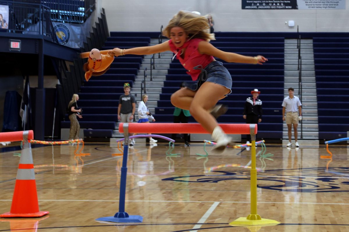 Senior Claire Cooper leaps over the hurdle to beat opposing groups and win the relay race at homecoming pep assembly, Friday, Oct. 3.