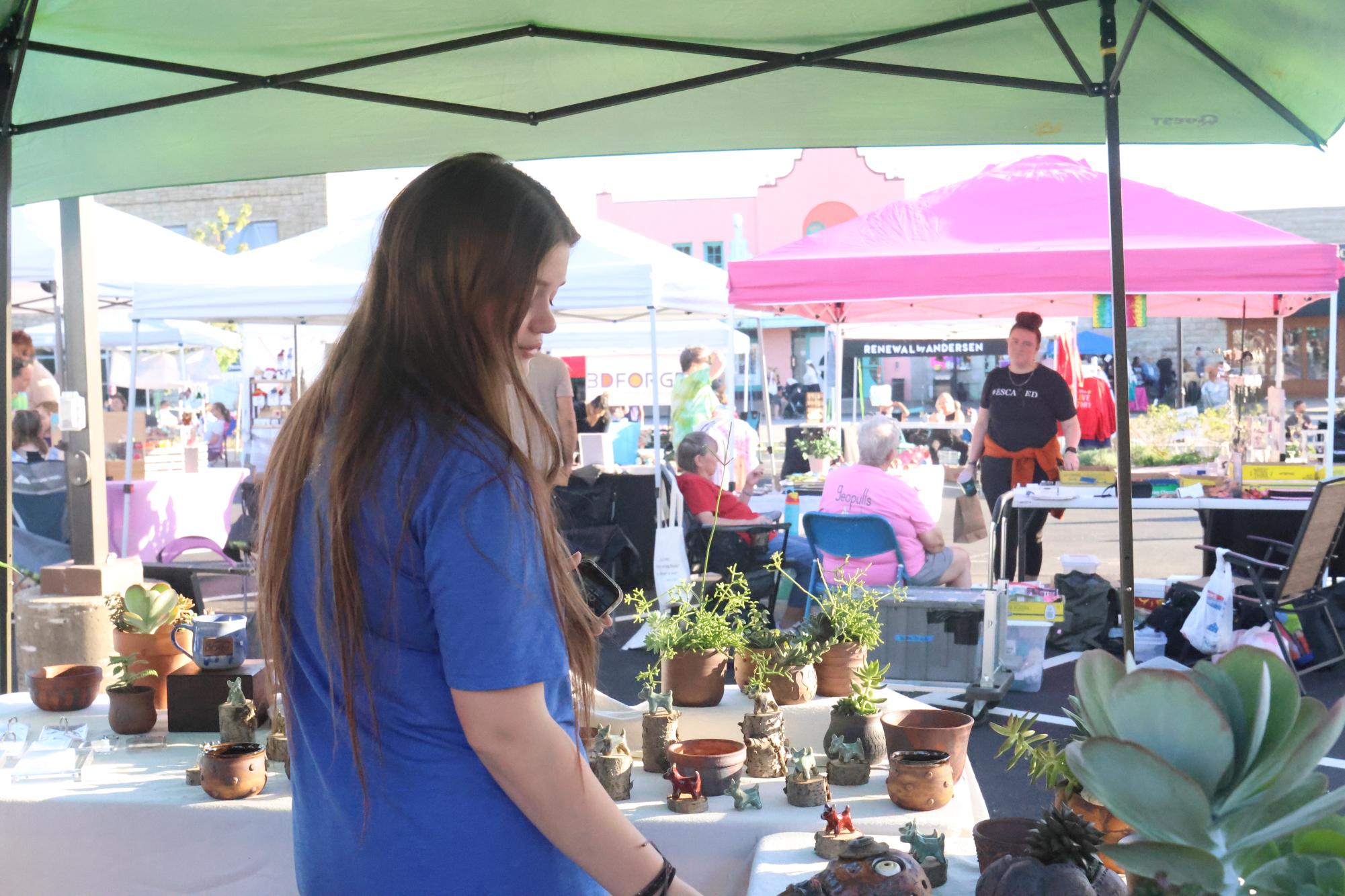 Senior Cat Rivas looks at a small plant business assortment of cacti and handmade ceramic skulls at Moonlight Market, Thursday Oct. 16. 