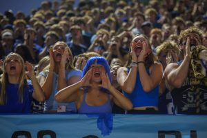 Shouting, the student section cheers on the football team. 
