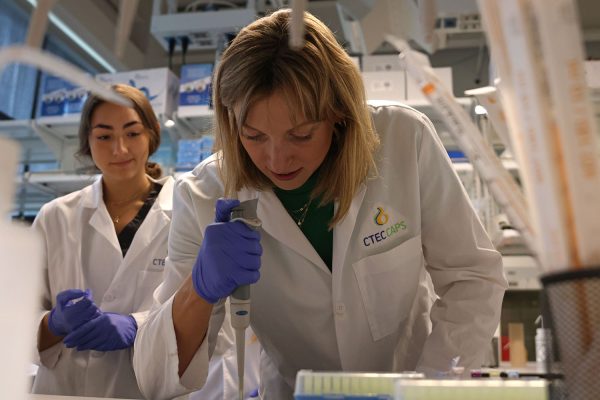 Leaning on the table, Katie Ledecky learns how to use a micropipette to pipe dyes onto a paper to create an image. 