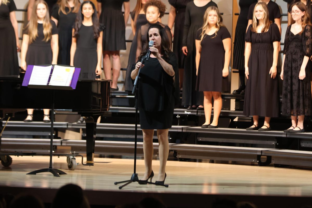 Getting ready to sing their first song for the night, choir teacher Laura VanLeeuwen says what they are going to perform. 