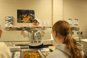 Standing behind the counter, Jillian Damaske serves students their lunch on Thursday, Oct. 9.