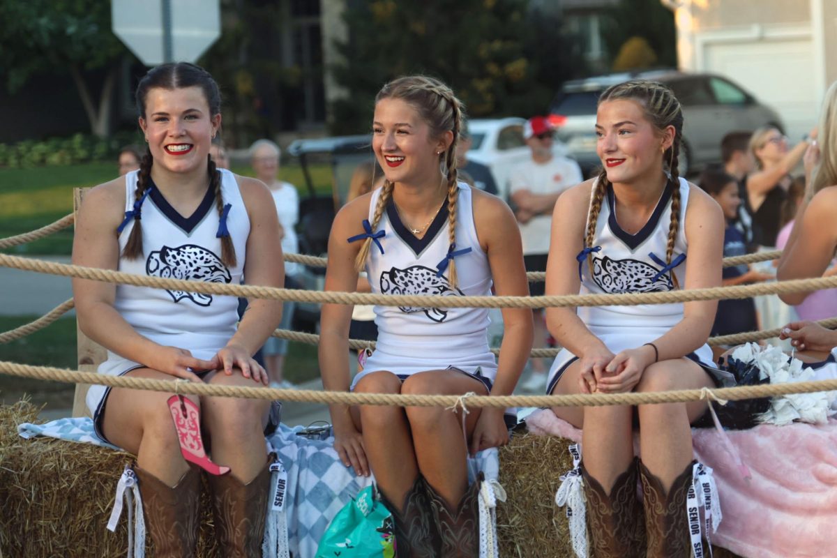 Smiling, seniors Kyndal Geis, Mallory Lux and Rachael Johnston look out to the crowd from the cheerleading float. 
