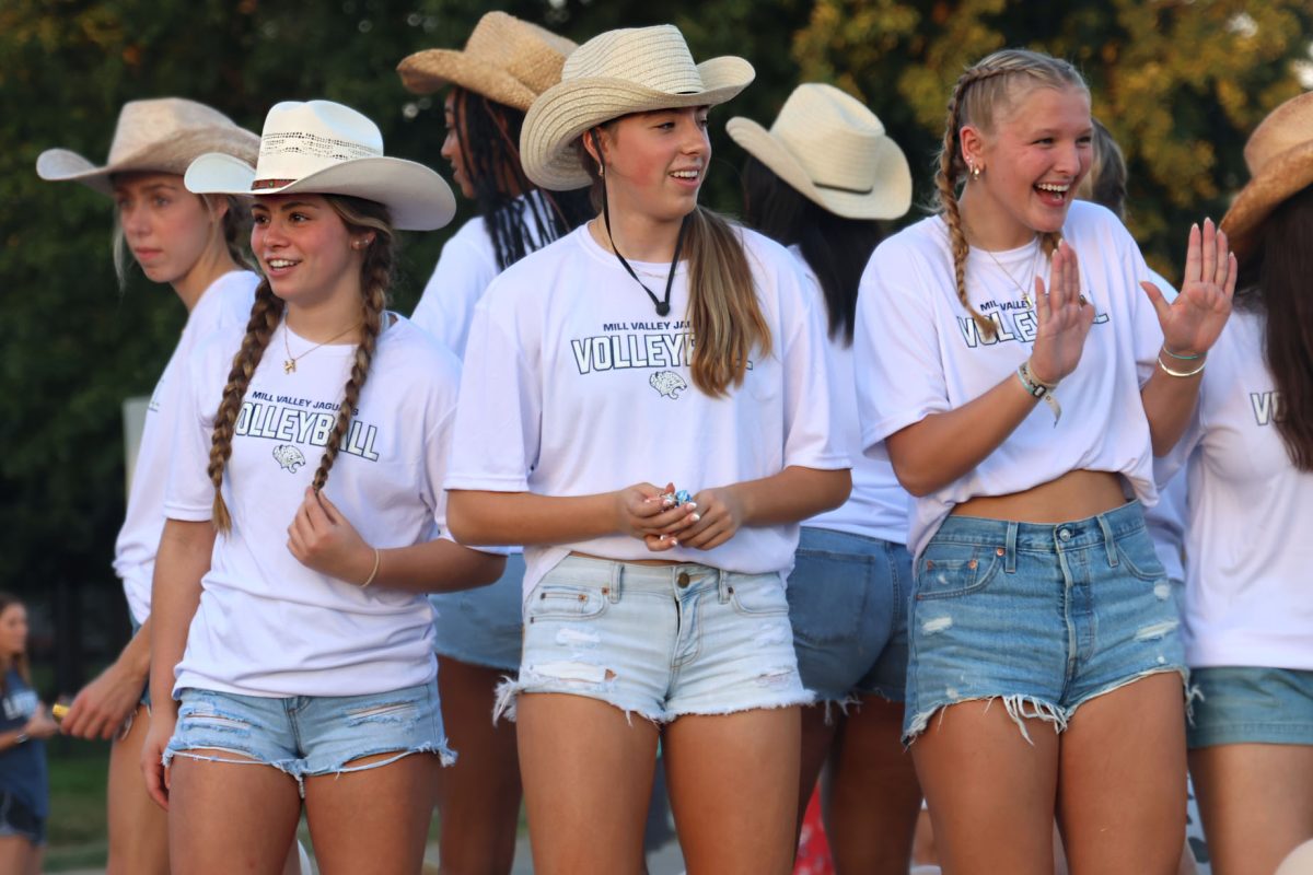 Sophomore Haedyn Lynnes, sophomore Ellie Bain and junior Josie Danielson smile at the crowd from the volleyball float. 