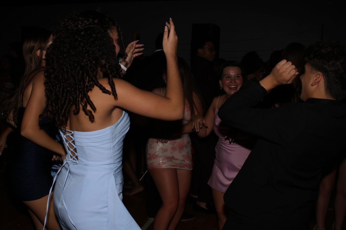 In a circle, sophomores Bella Page and Manny Raso dance, while senior Bianca Pepe cheers them on.