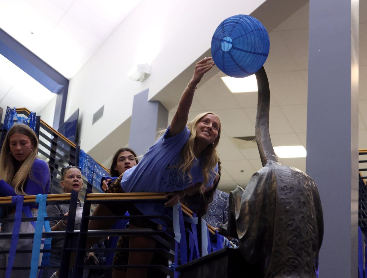 Hanging over the ledge, senior Jamie Ricker attempts to hang a lantern on the jaguar statue.