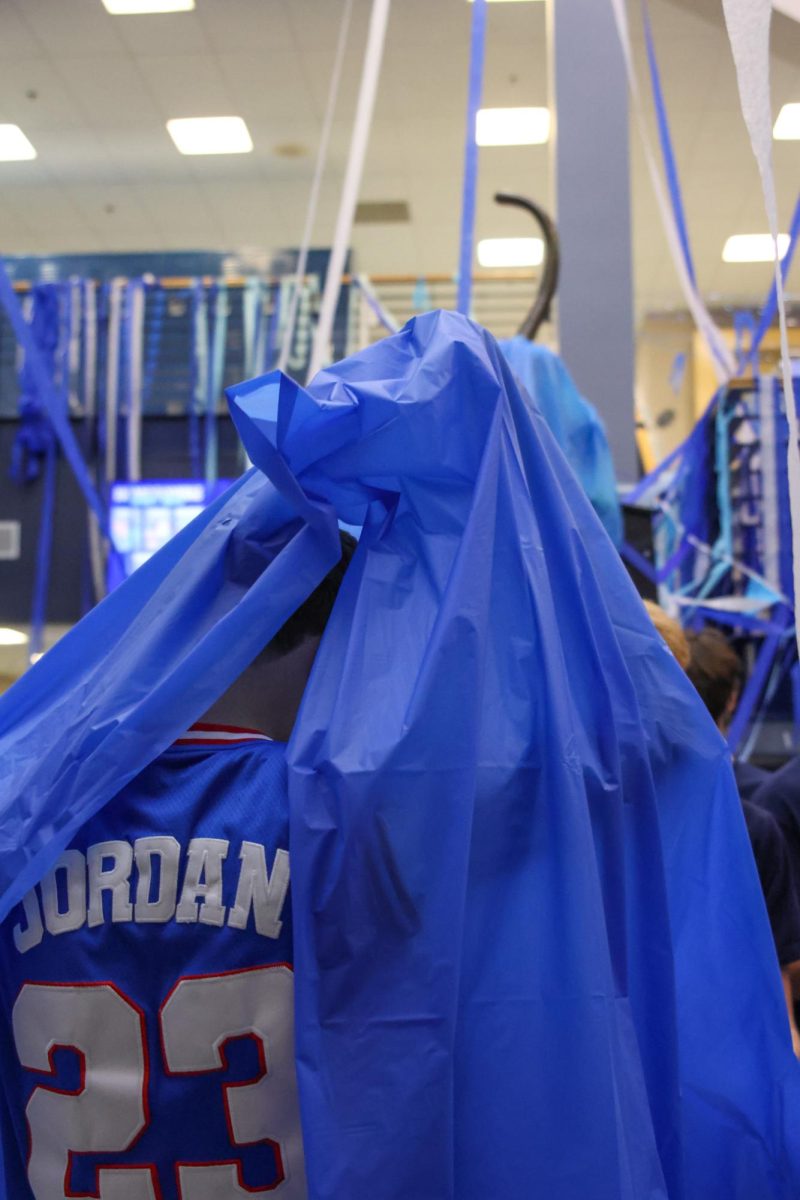 Covered in a blue tablecloth, senior Carter Clark attempts to get it off
