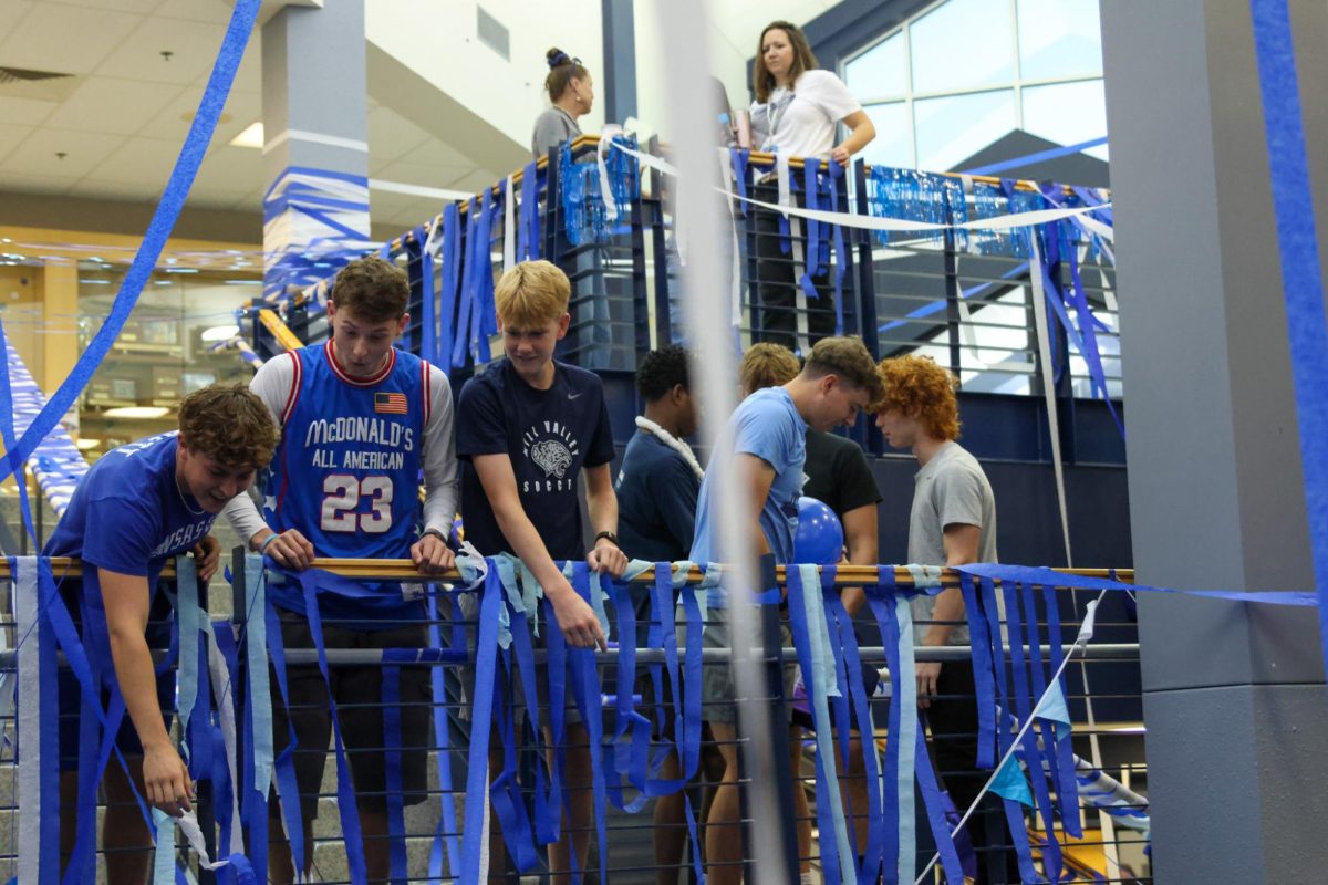 Leaning over the stair landing, seniors Carter Clark, Greyson Davis and Gavin Hurt stare down. 