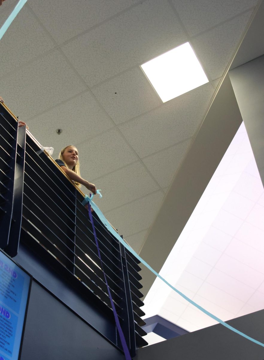 Senior Jenna Lloyd hangs a blue streamer at the start of Blue Bomb.
