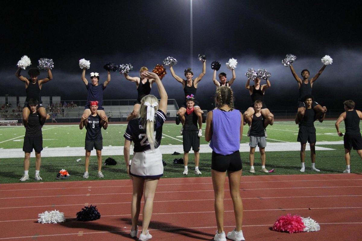 Standing on the sidelines junior and senior boys cheer on the girls as they come to the end of the second quarter. 
