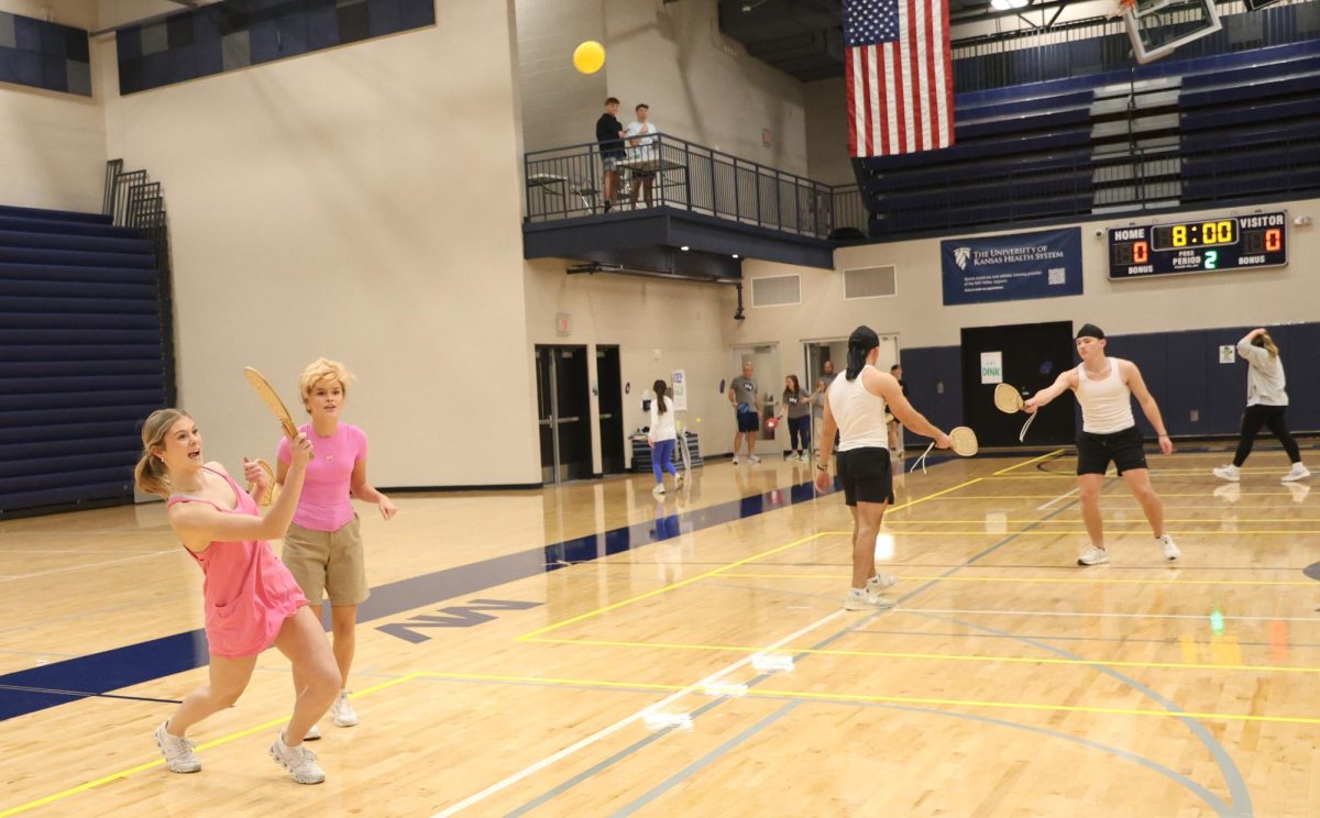 Striking the ball with the paddle, junior Kenna Long and junior Elliana Newell hit it across the net.
