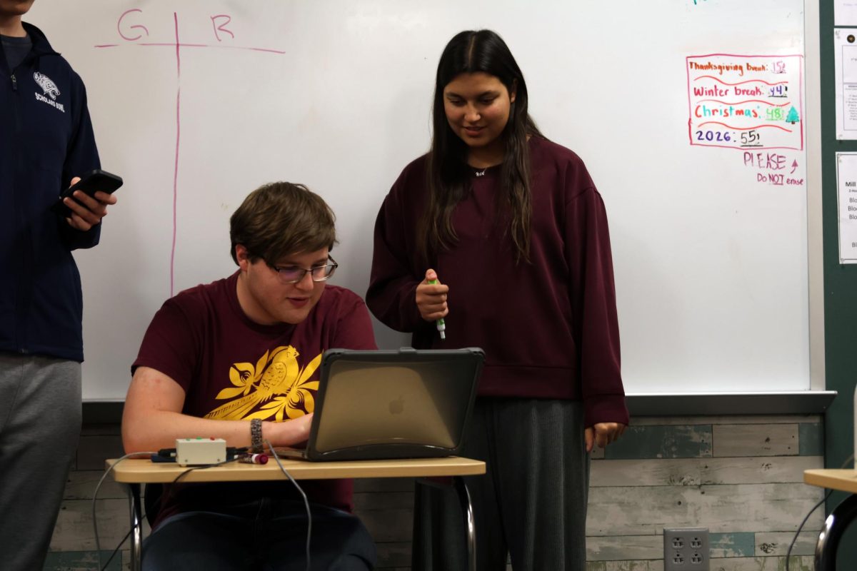 Seniors Nadia Kindt and Ian Weatherman search through documents to find questions for the next round.