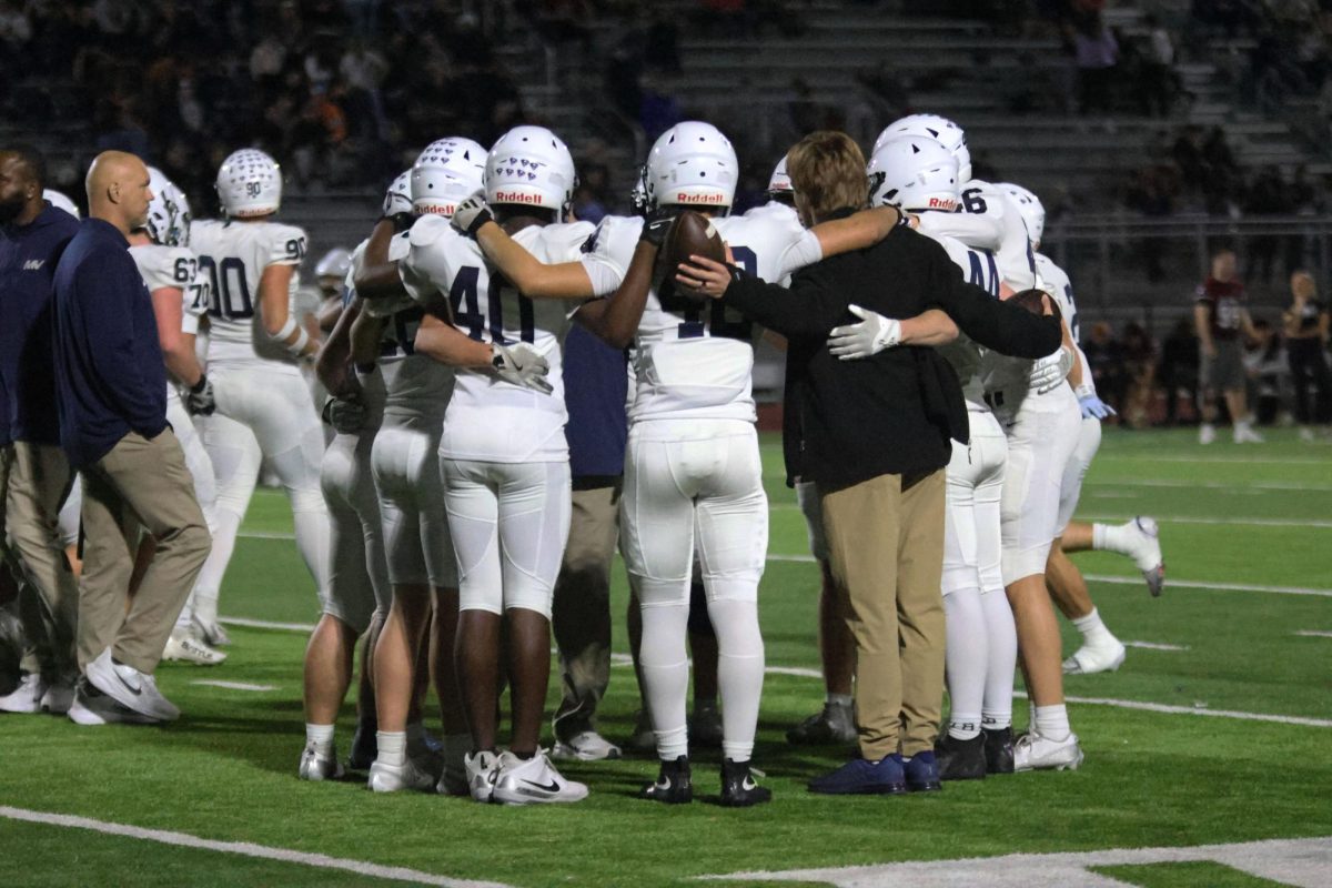 Players huddle on the field after the game is over.
