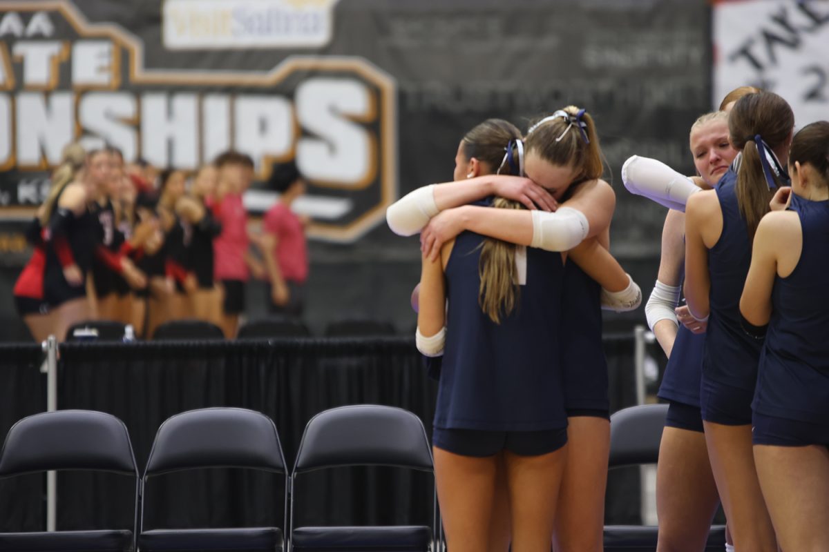 Senior Ella Florez and junior Riley Riggs share a hug after defeating Olathe Northwest.