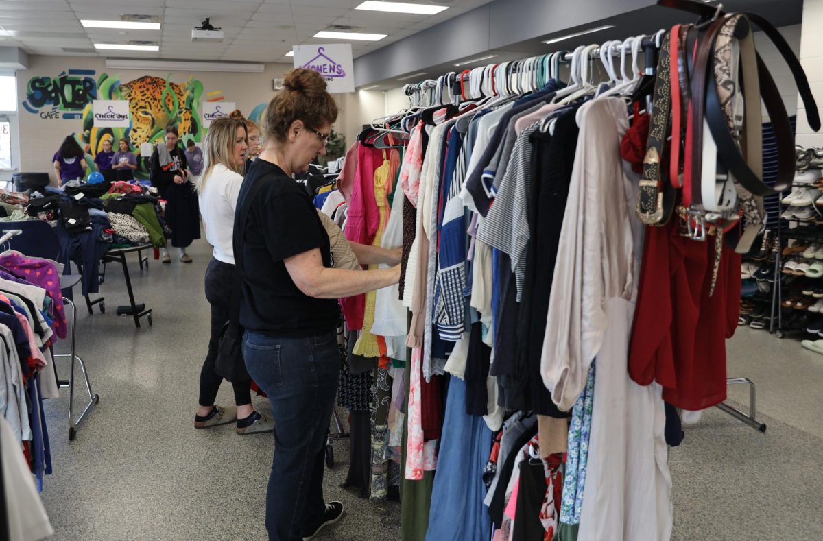 Women browse through the clothing rack, finding amazing finds. 