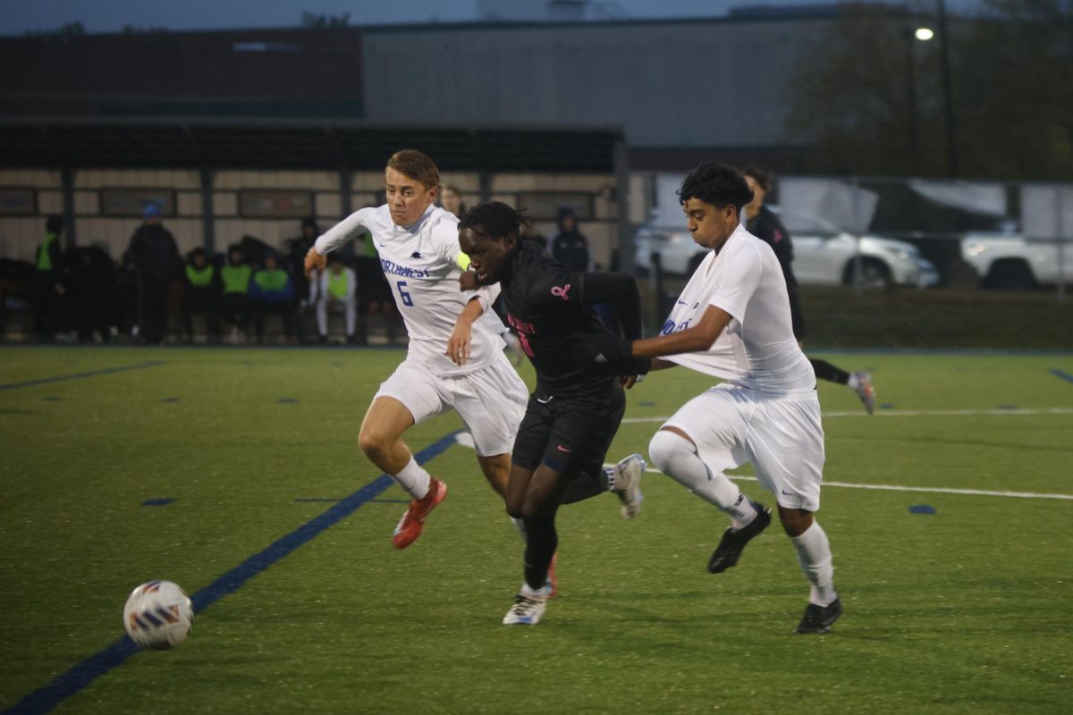 Senior Cayden Rotich dribbles down the field while being defended by Olathe Northwest. 
