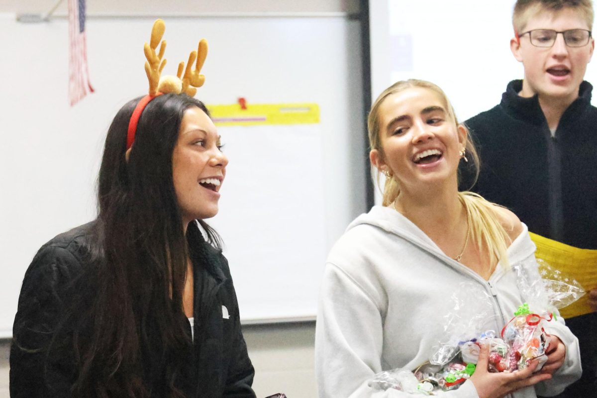 Seniors Stella Beins, Claire Cooper, and Elliot Fischer sing before they give out treats for their carol grams